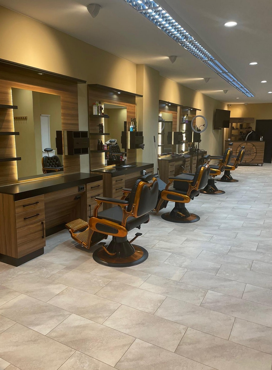 De rij houten werkplekken met oranje kappersstoelen bij Avi the Barber