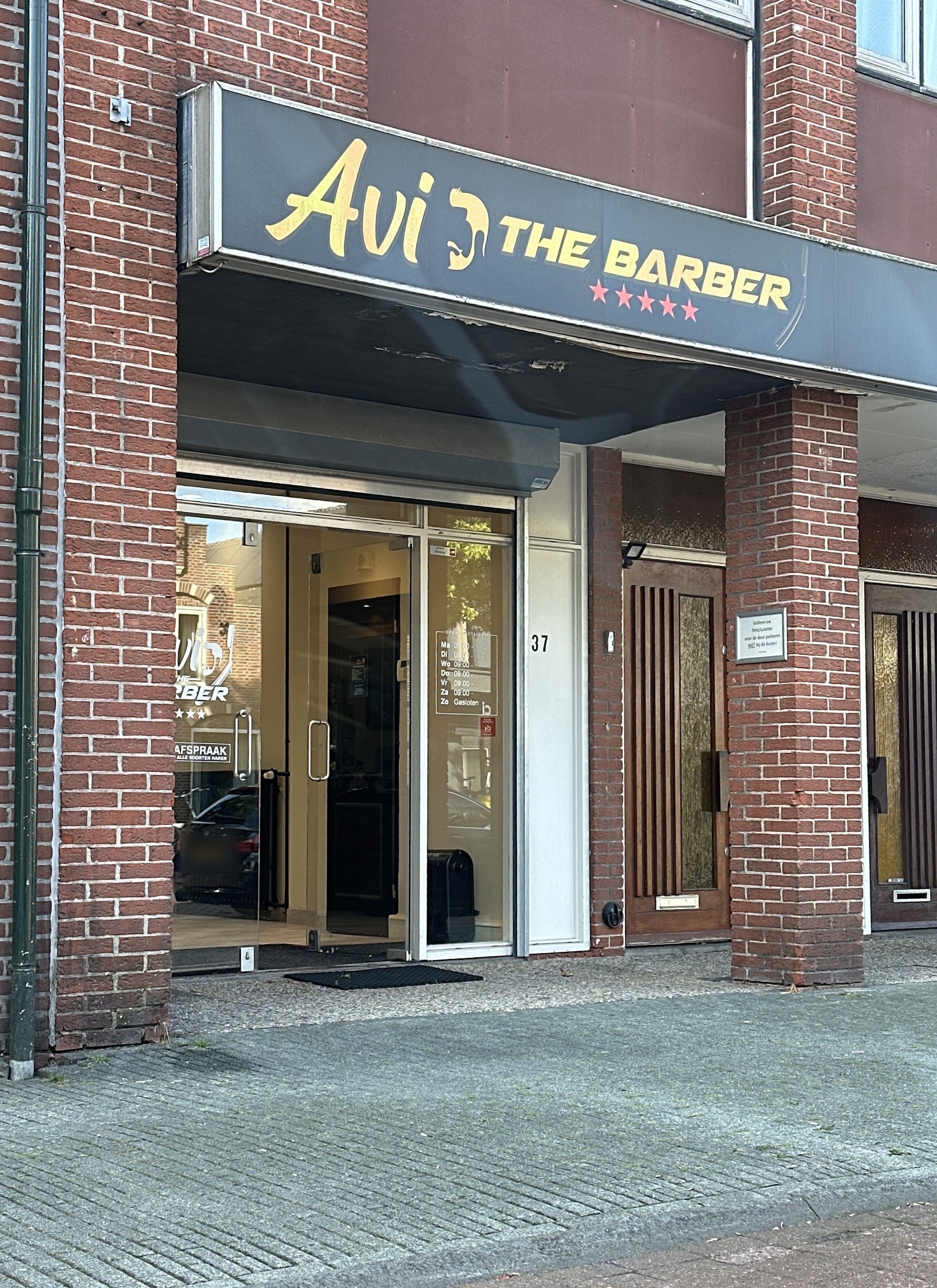 De gevel van Avi the Barber met het gouden bord boven de deur, Herenstraat 37