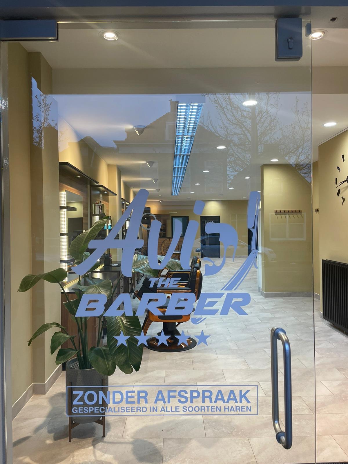 De glazen deur van Avi the Barber met de tekst Zonder afspraak, gespecialiseerd in alle soorten haren
